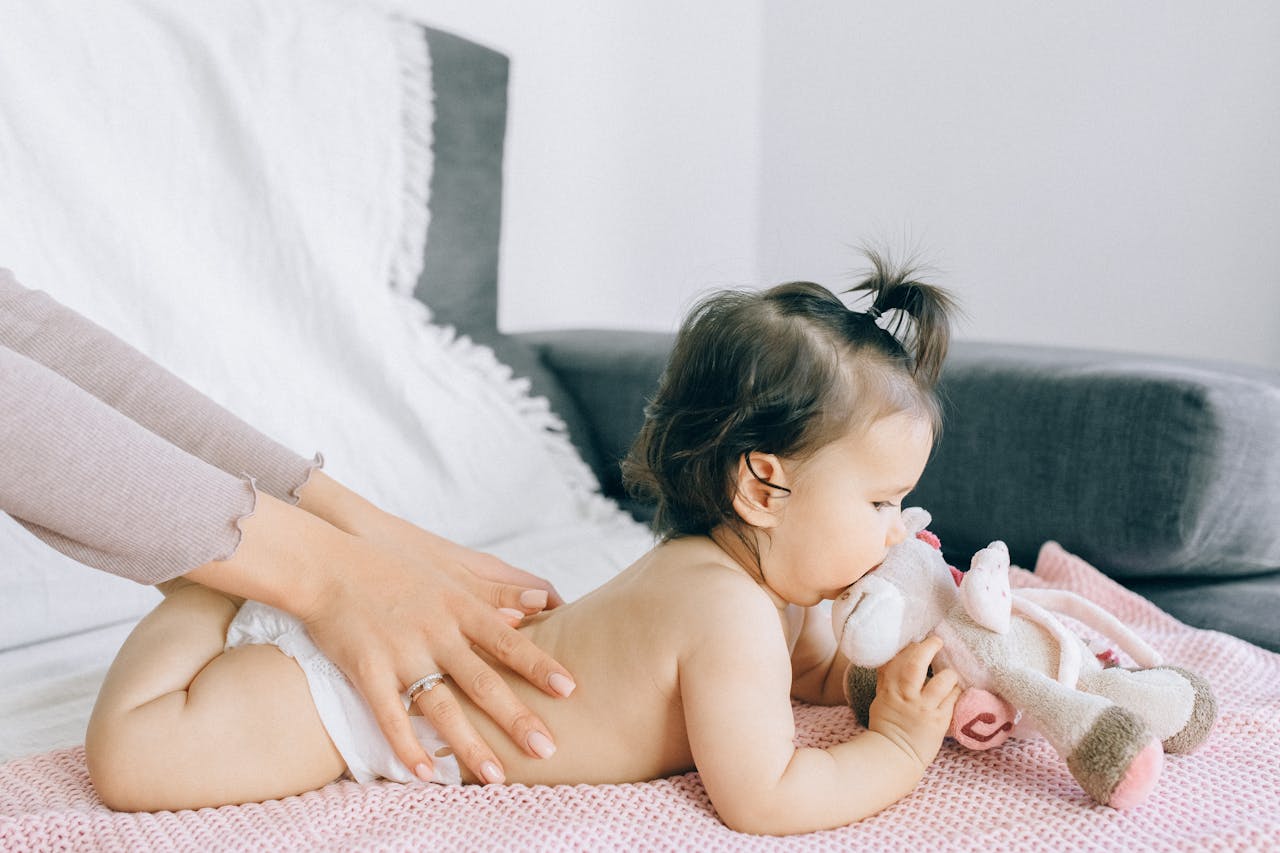 Offerings A serene moment of a baby receiving a gentle massage while holding a plush toy, epitomizing peace and comfort.